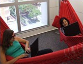 Duas mulheres deitadas na rede com notebook